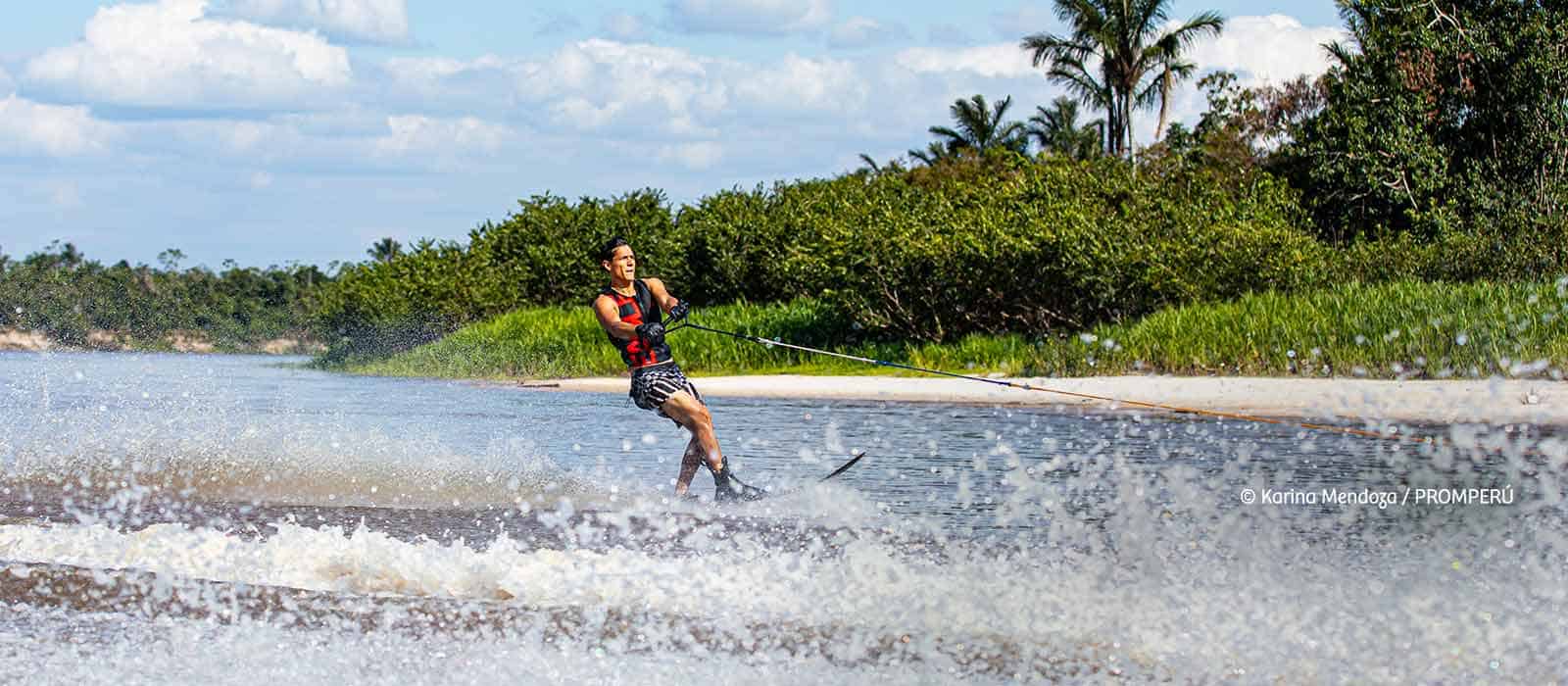 Persona practicando wakeboard en río de Loreto, Perú, disfrutando del deporte acuático en contacto con la naturaleza.
