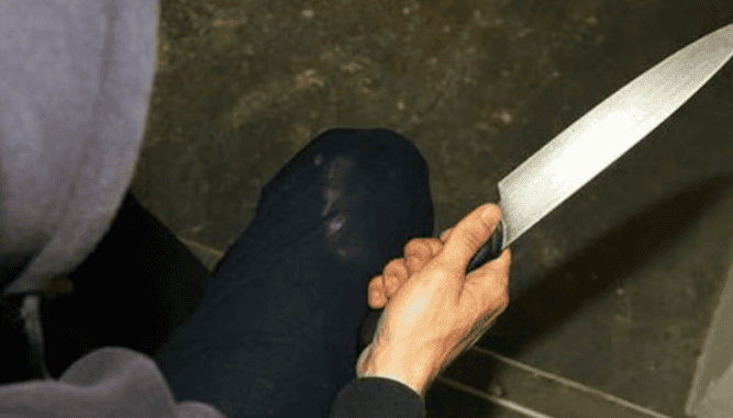 Cuchillo en mano, persona sentado en una silla en un ambiente cerrado, imagen que genera alarma y preocupación en Loreto Noticias.