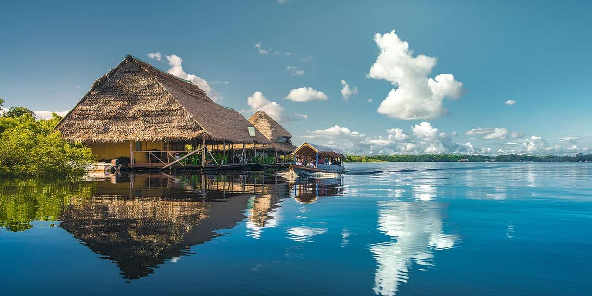 Artesanías en Loreto, Perú, en un mercado local sobre el río Amazonas con casas tradicionales de palma y un paisaje pintoresco.