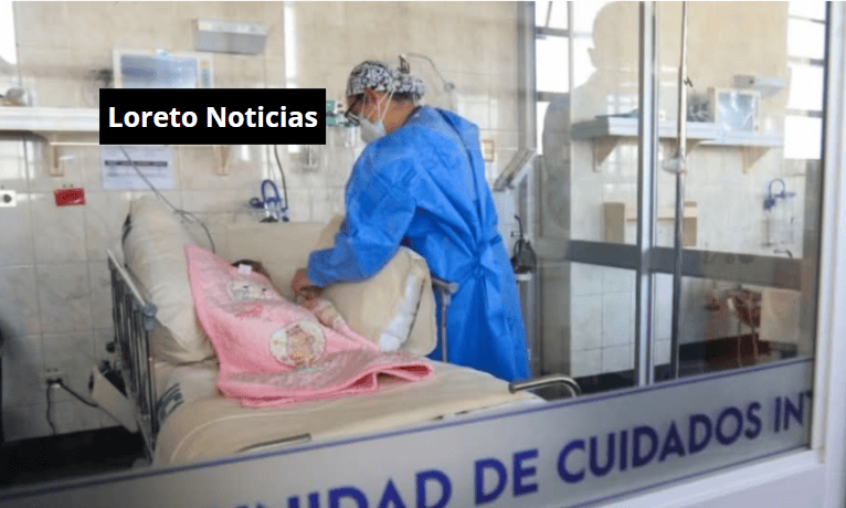 Paciente en cama recibiendo atención médica en hospital, personal sanitario con uniforme y mascarilla, ambiente de cuidados intensivos, imagen relevante para noticias sobre salud en Loreto Noticias.