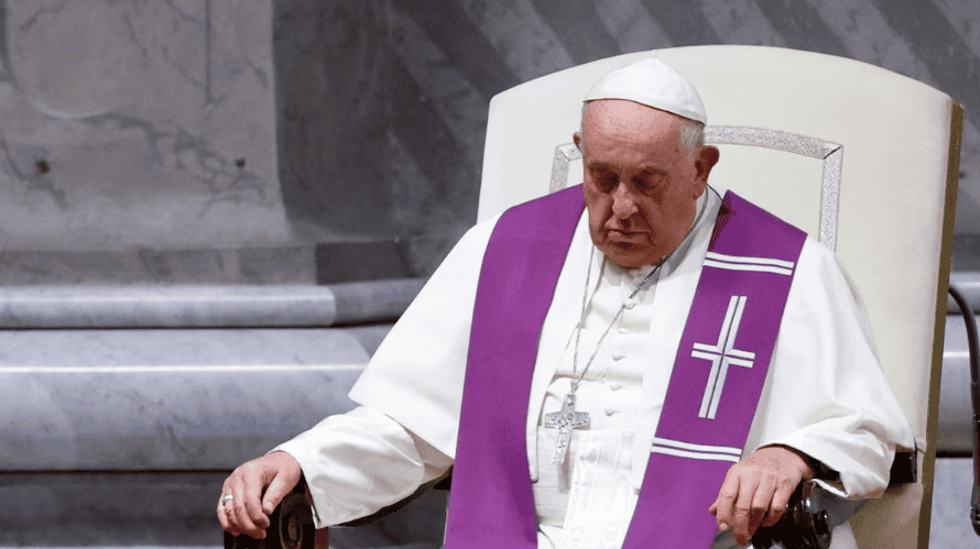 Papa Francisco en audiencia papal, sentado con gesto serio, vistiendo vestimenta religiosa blanca y morada con cruz, en un entorno eclesiástico, en una postura reflexiva y solemne.