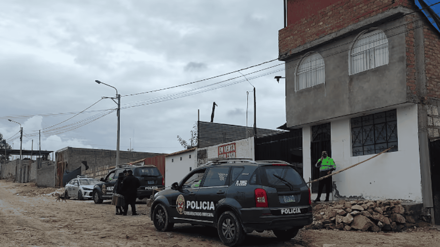 Policías en la escena de un incidente en Loreto Noticias, en una calle de zona urbana con coches y personas, bajo un cielo nublado, investigando un acontecimiento importante en Loreto, Perú.