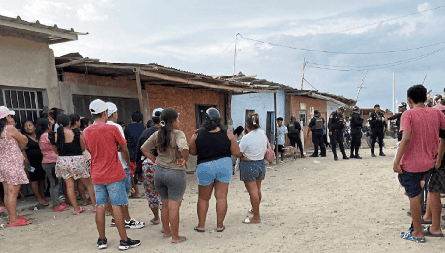 Puerta de vivienda en Loreto, protagonizada por una multitud de personas y policías en un entorno rural de Perú, en medio de una actividad social o problemática comunitaria.