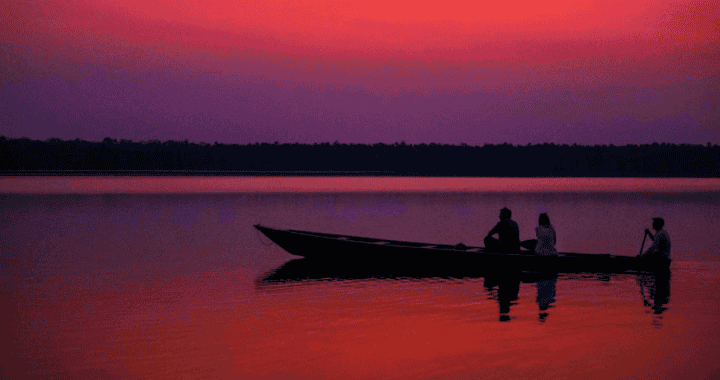 Barco en laguna durante atardecer en Loreto, Perú, con personas disfrutando del paisaje y la tranquilidad del agua, en un entorno natural y pintoresco.