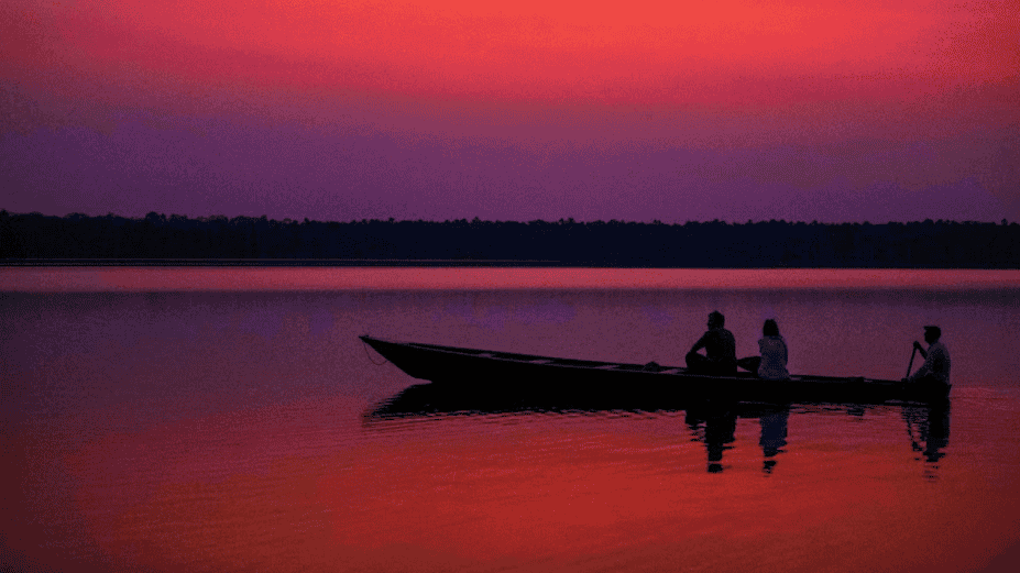 Barco en laguna durante atardecer en Loreto, Perú, con personas disfrutando del paisaje y la tranquilidad del agua, en un entorno natural y pintoresco.