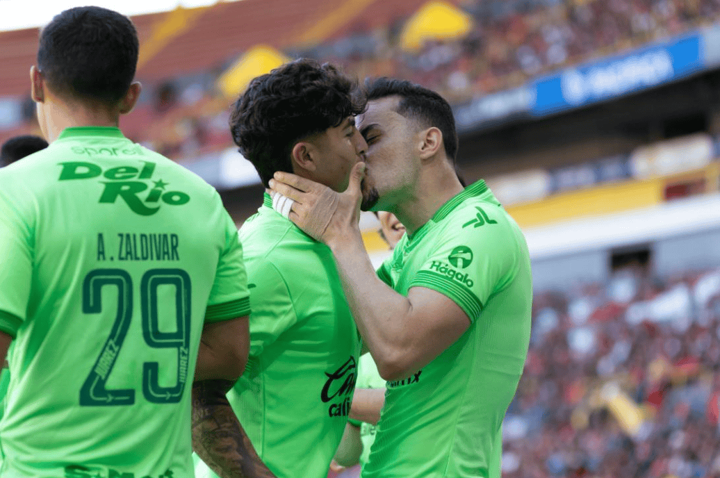 Amor y celebración en el fútbol peruano: jugadores de Loreto Noticias en un emotivo momento en el campo con camisetas verdes y aplausos en el estadio.