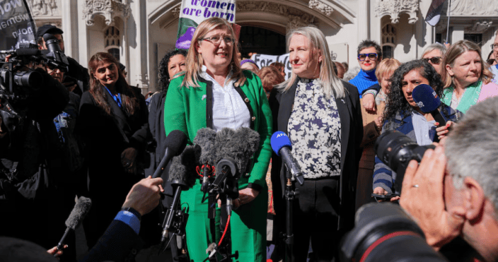 Manifestantes feministas en una protesta frente a un edificio histórico, con varias mujeres y periodistas en el lugar, promoviendo derechos de las mujeres y igualdad de género en Loreto Noticias.