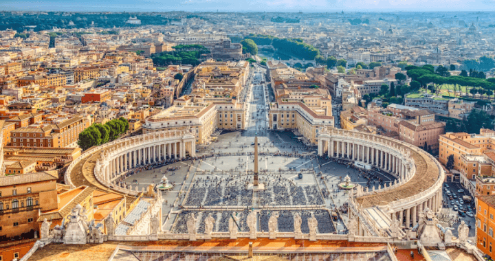 Cielo despejado sobre el Vaticano en Roma, Italia, con turistas en la Plaza San Pedro y edificios históricos, ofreciendo vista panorámica y contexto cultural.