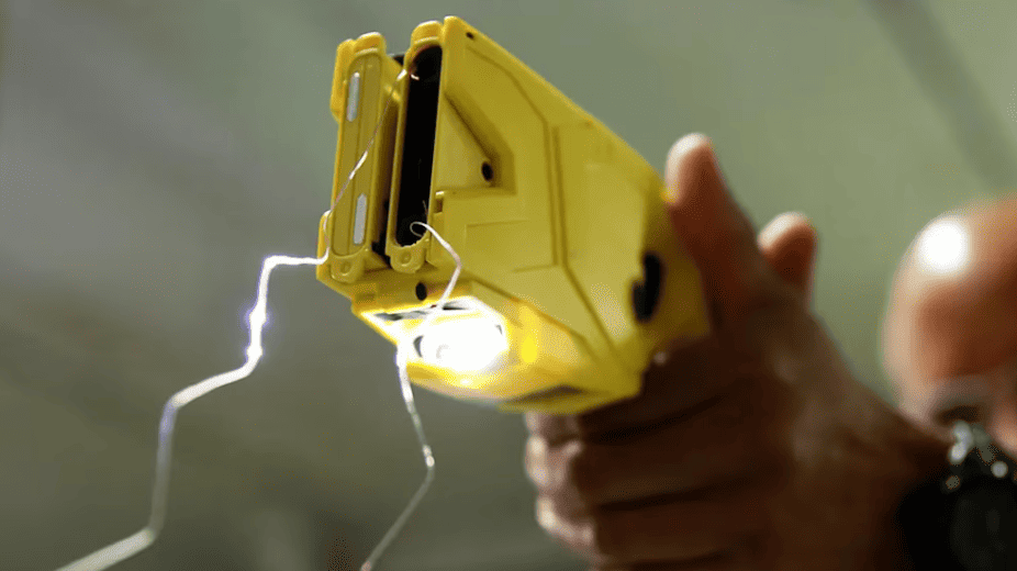 Arma de descarga eléctrica en mano, simulando un dispositivo electrizante para captura o asalto. Imagen que transmite tensión y peligro en escenarios de seguridad y vigilancia.