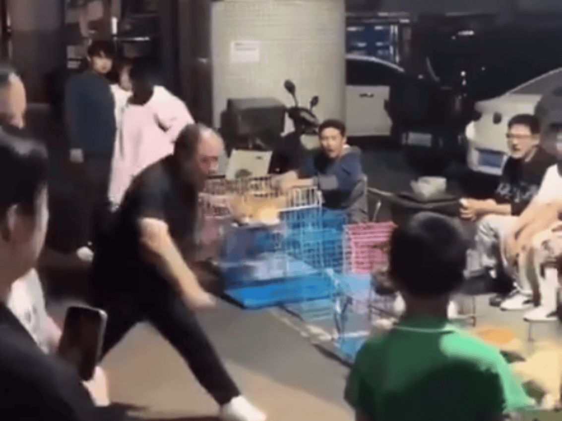 Persona lanzando objetos en una calle de Loreto, Perú, rodeada de varias personas observando y grabando, en un entorno urbano, posiblemente en un incidente de confrontación o protesta.