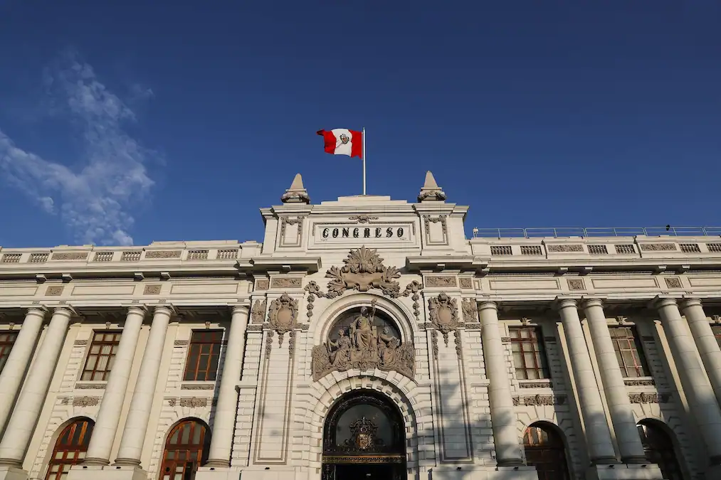 Edificio del Congreso de Perú con bandera peruana, arquitectura colonial, sede del poder legislativo peruano, monumento histórico en Lima.