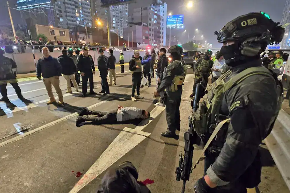 Muertos en escena de un incidente policial en una calle de Lima, Perú, con oficiales de la policía y personas observando. La imagen muestra un escenario de emergencia y seguridad en una vía urbana.