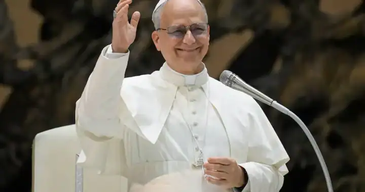 Papa Francisco en audiencia papal saludando con una sonrisa, vistiendo su vestimenta papal blanca y lentes de sol, en un evento oficial en el Vaticano.