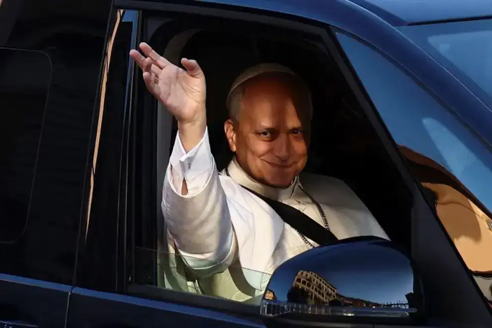 Hombre en coche saludando con sonrisa en un día soleado.
