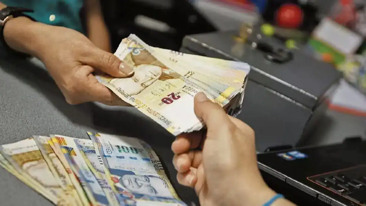 Dinero en efectivo de soles peruanos, manos intercambiando billetes en una transacción financiera en Loreto Noticias.