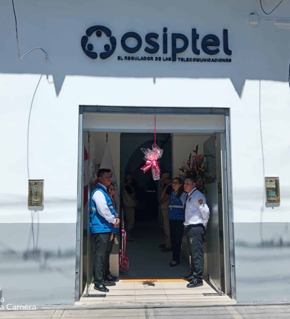 Puerta de oficina de OSIPTEL en Loreto, con personal de telecomunicaciones en casaca azul, durante inauguración o evento oficial en Loreto Noticias.