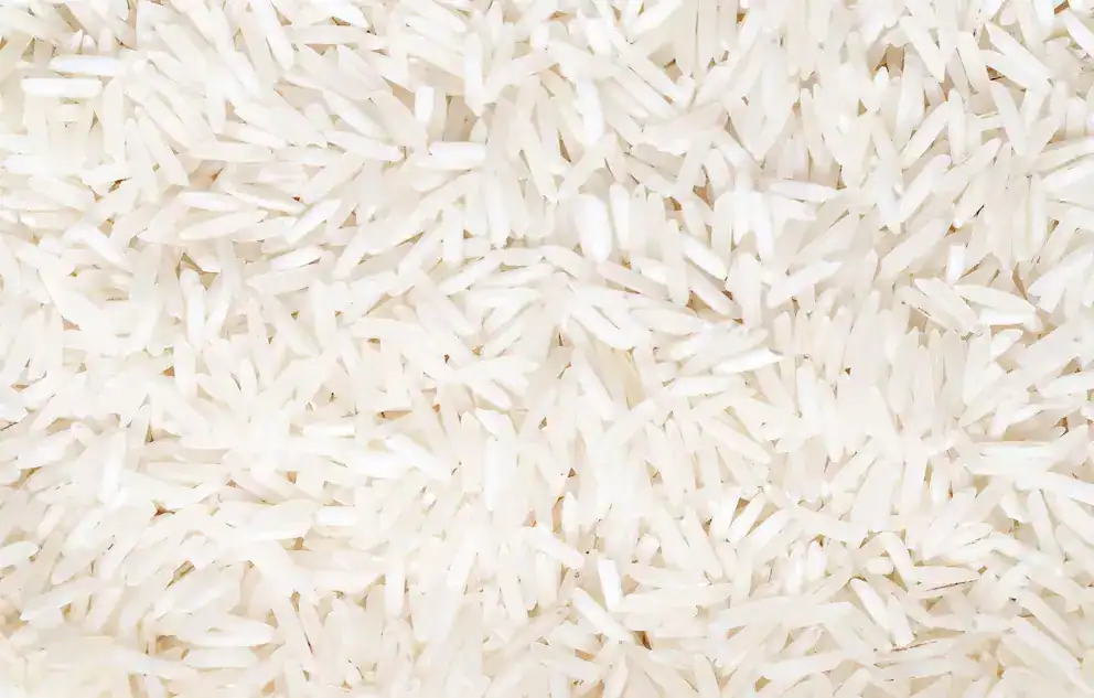 Arroz blanco crudo en granos sueltos, ideal para cocinar, en una fotografía cercana y detallada.
