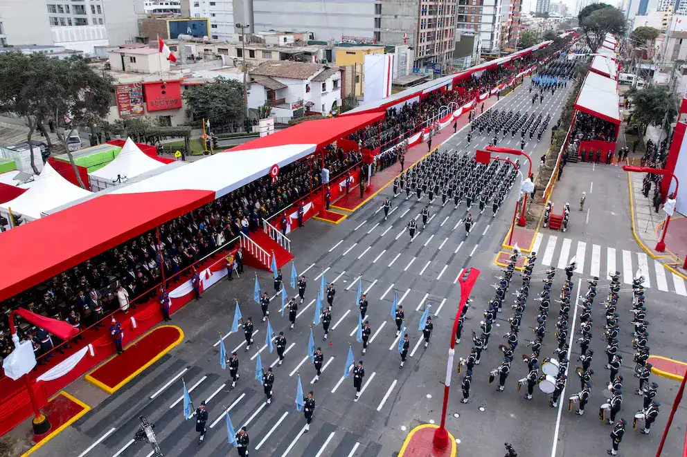 Marcha militar en calle principal de Loreto, Perú, con soldados en formación durante ceremonia oficial en celebración cívica y militar.