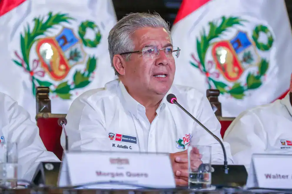 W. Astudillo C. en evento político en Loreto, Perú, con banderas nacionales y logotipos oficiales al fondo, participando en conferencia de prensa o reunión institucional importante.