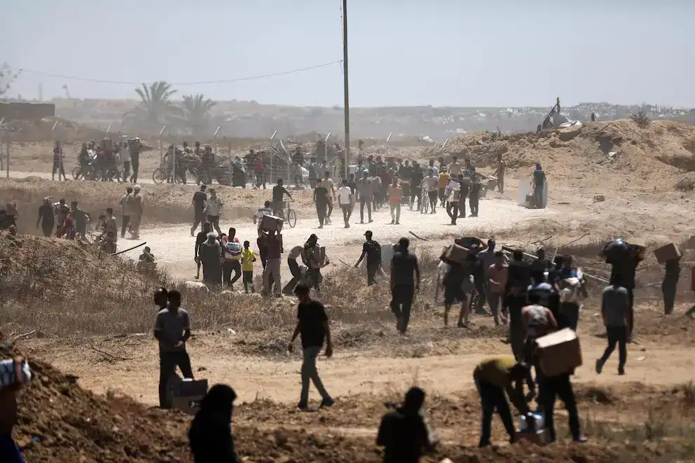 Camino polvoriento en Loreto con muchas personas cargando objetos, en un entorno árido y arenoso, en medio de un contexto de movilidad y traslado en Perú.