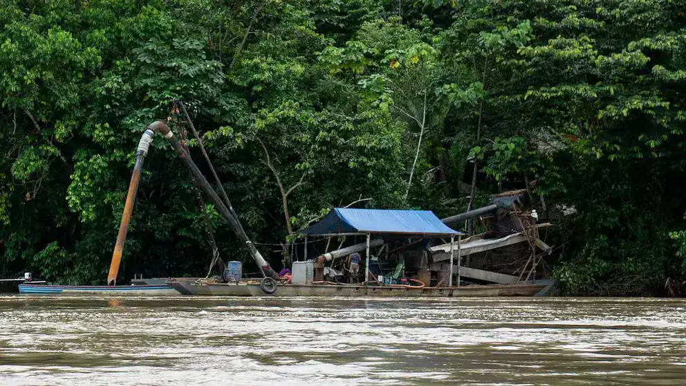 Barcaza en el río Loreto con estructura de madera y techado azul rodeada de vegetación densa en la selva amazónica peruana.