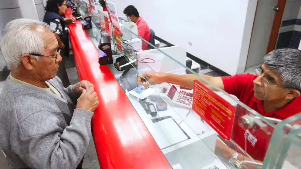 Recibo de atención en oficina bancaria, cliente realiza transacción financiera en ventanilla con atención especializada en Perú.