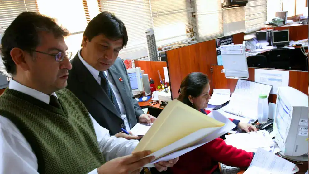 Archivos administrativos en oficina de Loreto Noticias con empleados revisando documentos, trabajo en escritorio, prensa regional, gestión informativa.