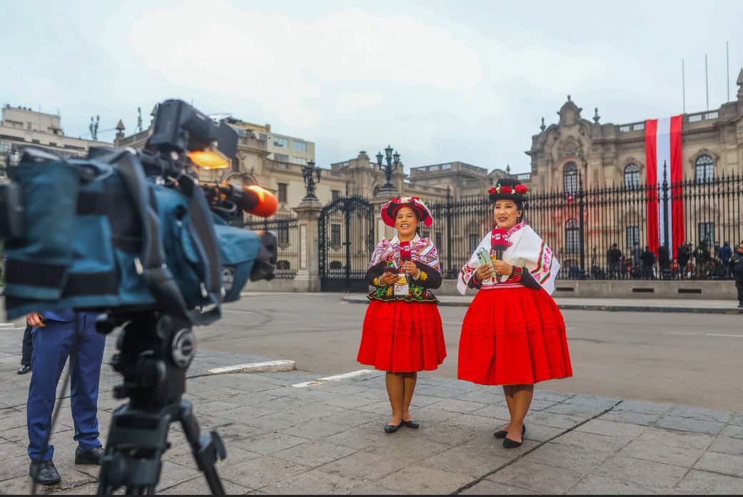 Vestidas con trajes tradicionales peruanos, dos mujeres sonrientes en Plaza Mayor durante celebración nacional en Lima, Perú. Fotografía de Loreto Noticias.