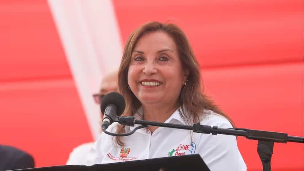 Loreto Noticias: mujer sonriente en evento público, participando en actividad comunitaria o política, con fondo rojo y micrófono, destacando liderazgo y participación social en Loreto.
