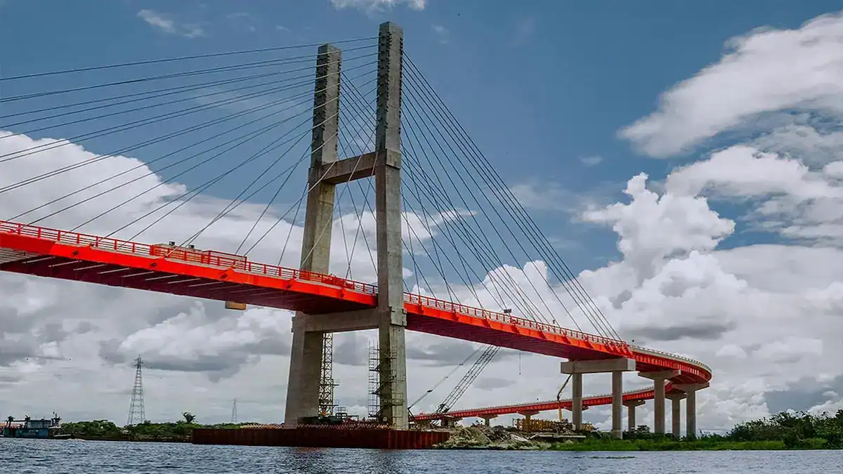 Puente colgante en Loreto, Perú, sobre río con cielo despejado, muestra infraestructura moderna y vanguardista en desarrollo.