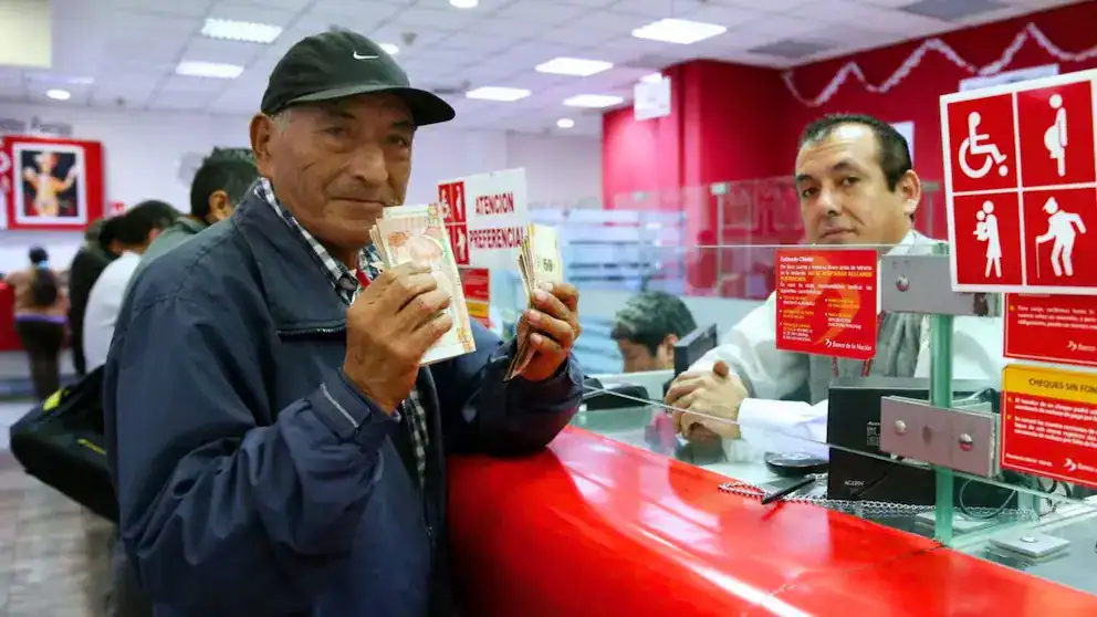Billete de nuevo sol peruano en mano en oficina bancaria en Loreto, Perú. Cliente satisfecho con servicio de gestión financiera en Loreto Noticias, destacando economía local.