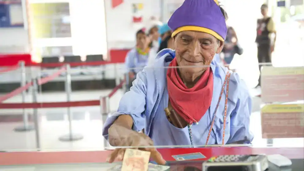 A1. joven adulta usando ropa tradicional y accesorios en un establecimiento público en Loreto, Perú, participando en una actividad cultural o comercial, con otras personas en el fondo.