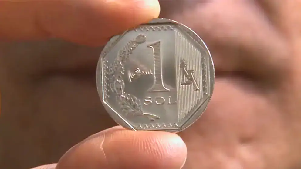 1. imagen de una moneda de 1 sol peruano sendo mostrada por una mano, fondo de piel, detalles visibles del diseño y tamaño de la moneda, cultura e historia peruana.