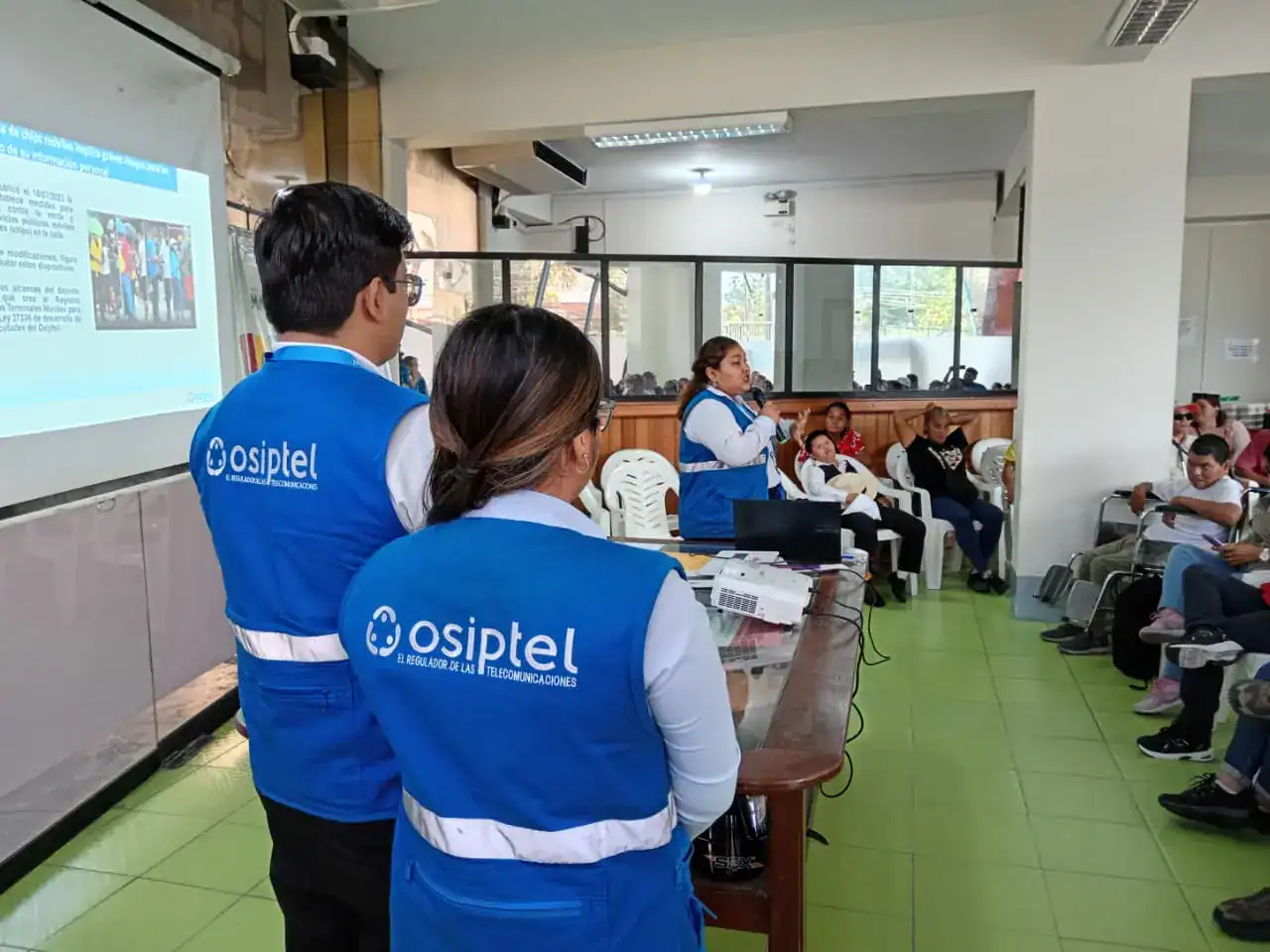 Infraestructura de capacitación en Loreto Noticias, con personal de Osiptel brindando información sobre regulaciones de telecomunicaciones a la comunidad local en un entorno escolar.