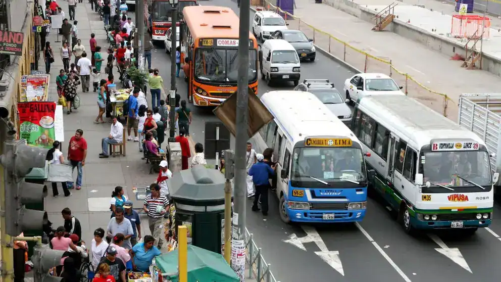 Transporte público en Lima, tránsito congestionado en la vía principal, gran afluencia de pasajeros en paraderos y vendedores ambulantes en la acera, reflejando la dinámica diaria de movilidad urbana en Loreto Noticias.