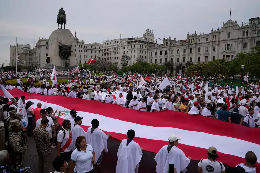 Grandes manifestantes en la Plaza Mayor de Lima con bandera peruana, participando en marcha patriotica por la independencia del Perú.