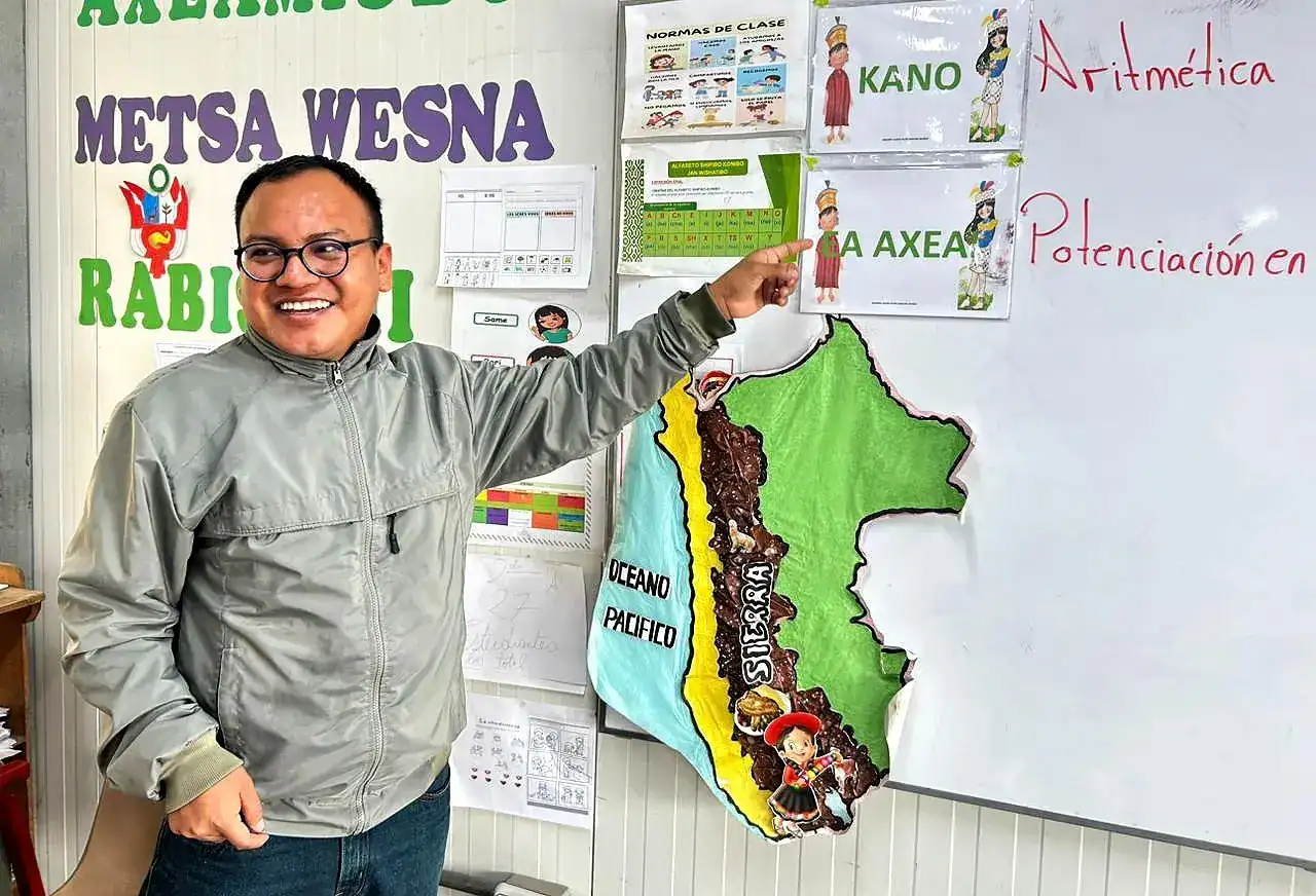Diseñador enseñando mapa del Perú en aula escolar, promoviendo educación en geografía y cultura local en Loreto, Perú, para incentivar el aprendizaje infantil y fortalecer identidad regional.