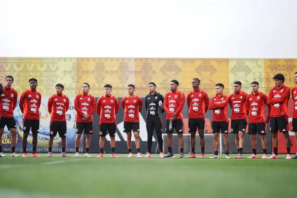 Jugadores de fútbol de Perú en entrenamiento, equipo nacional vistiendo camisetas rojas durante la práctica en el campo deportivo.