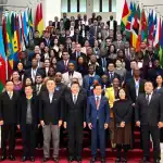 Diversos líderes y delegados internacionales en una reunión oficial con banderas de varios países en un evento multilateral importante.