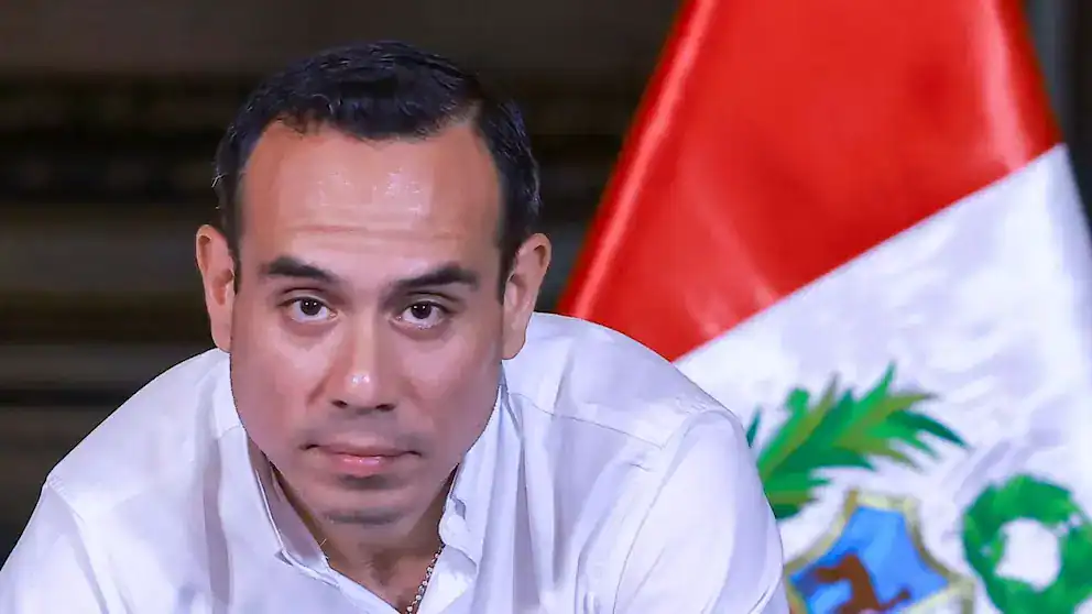 Diputado peruano en conferencia, frente a la bandera de Perú, discurso político, noticias de Loreto, escenario de autoridad, actualidad política peruana.