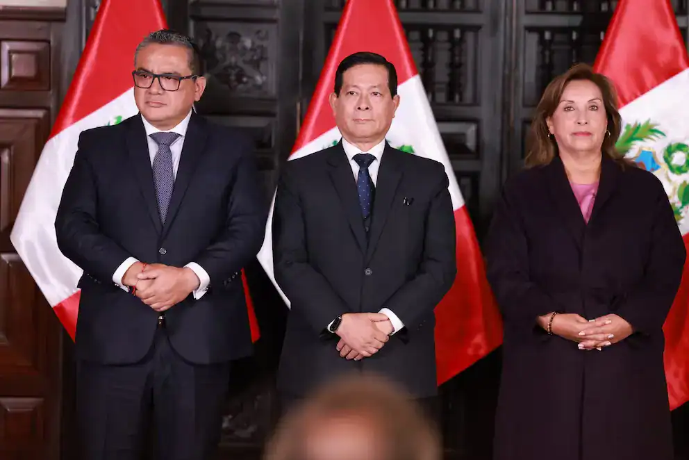 Peru autoridades gobierno discurso en evento oficial con banderas nacionales en el fondo.
