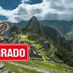 Vista de Machu Picchu con nubes y montañas verdes, patrimonio cultural, turismo en Perú, maravilla del mundo, majestuoso paisaje andino.