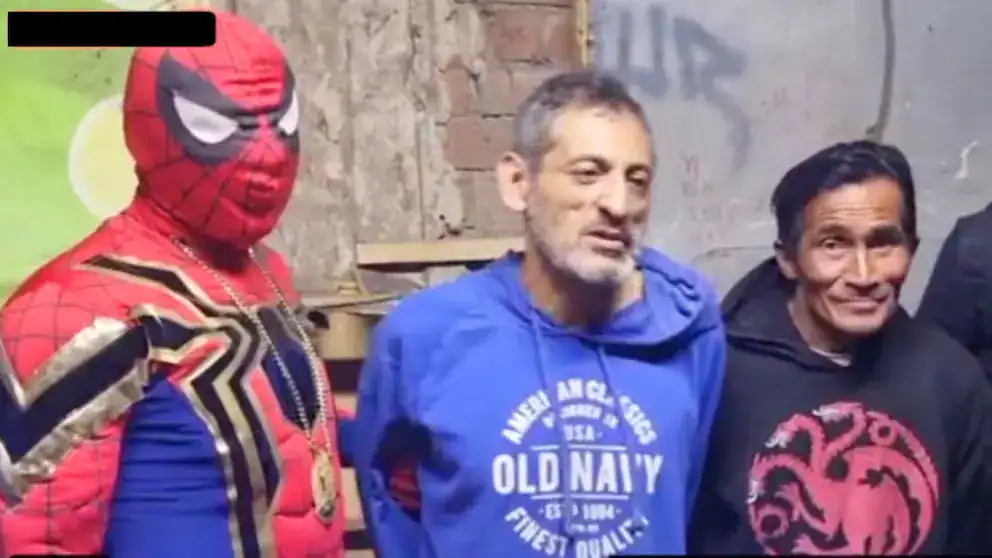 Disfraz de Spider-Man, estilo del superhéroe, vistiendo una camiseta azul con el logo de Old Navy, y acompañados por otros hombres, en un ambiente informal.