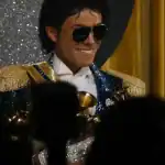 Disfraz de concierto en verano con gafas de sol, corbata y chaqueta brillante, estilo fiesta o celebración con fondo dorado y luces.