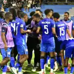 Jugadores de fútbol profesional en el campo durante un partido en Loreto, Perú, mostrando el apoyo y trabajo en equipo en un escenario deportivo.